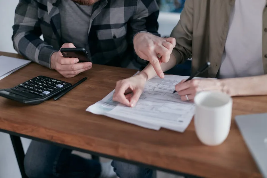A couple reviews paperwork at a wooden desk, possibly discussing mohs surgery cost. A calculator, phone, and mug are also visible.